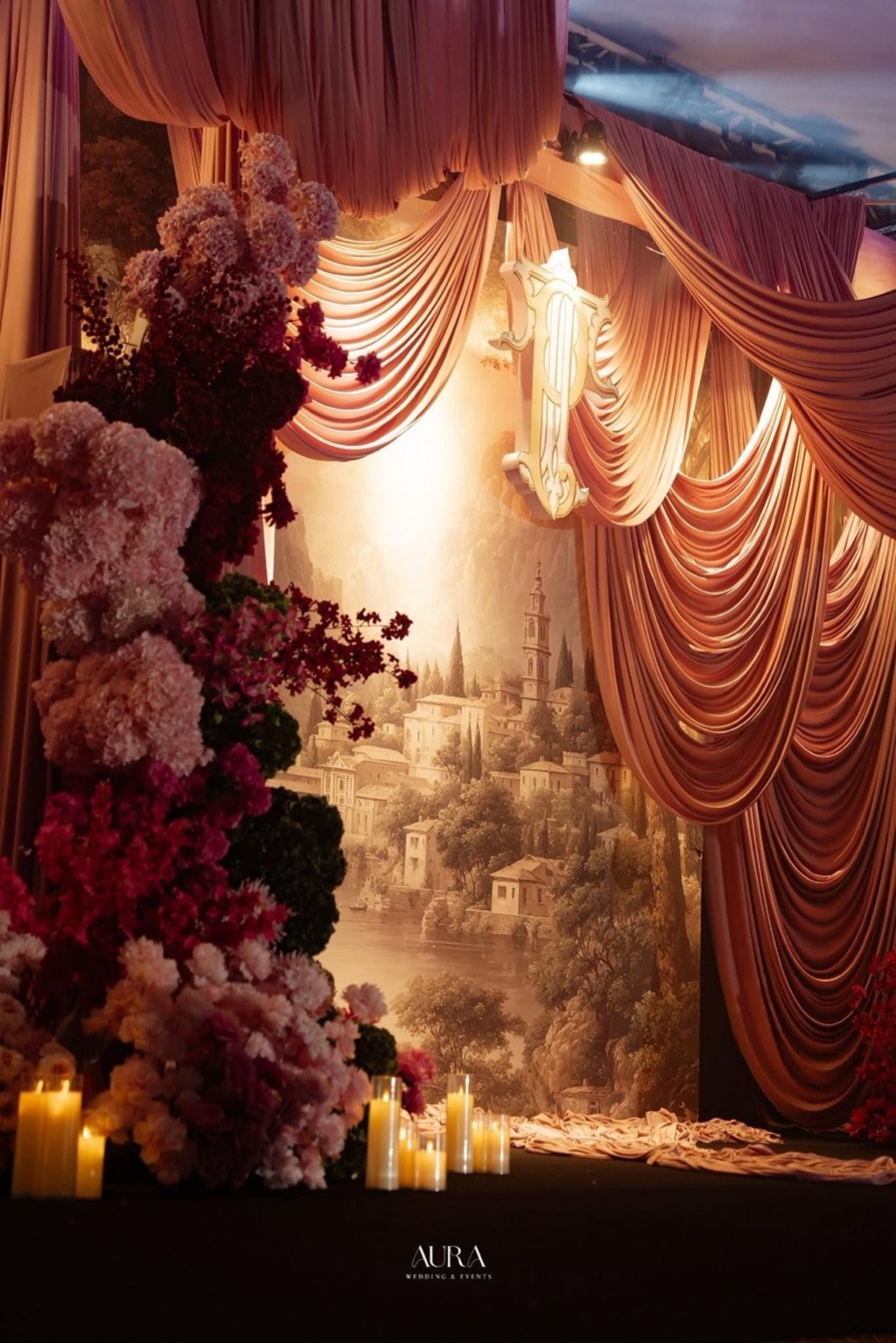 A Rose Affair — Trụ hoa cẩm tú cầu và hoa hồng nhiều sắc hồng – đỏ rượu bên rèm lụa hồng buông rủ và hàng nến trụ