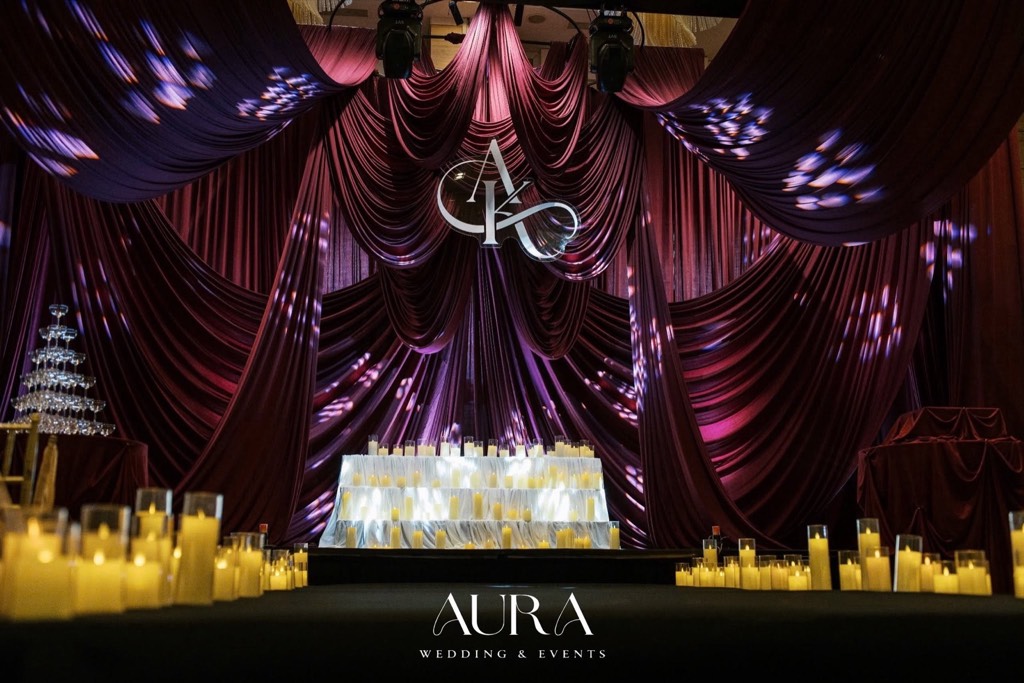 Sân khấu rèm nhung đỏ Burgundy xếp lớp, monogram AK, bức tường nến trắng và tháp ly champagne
