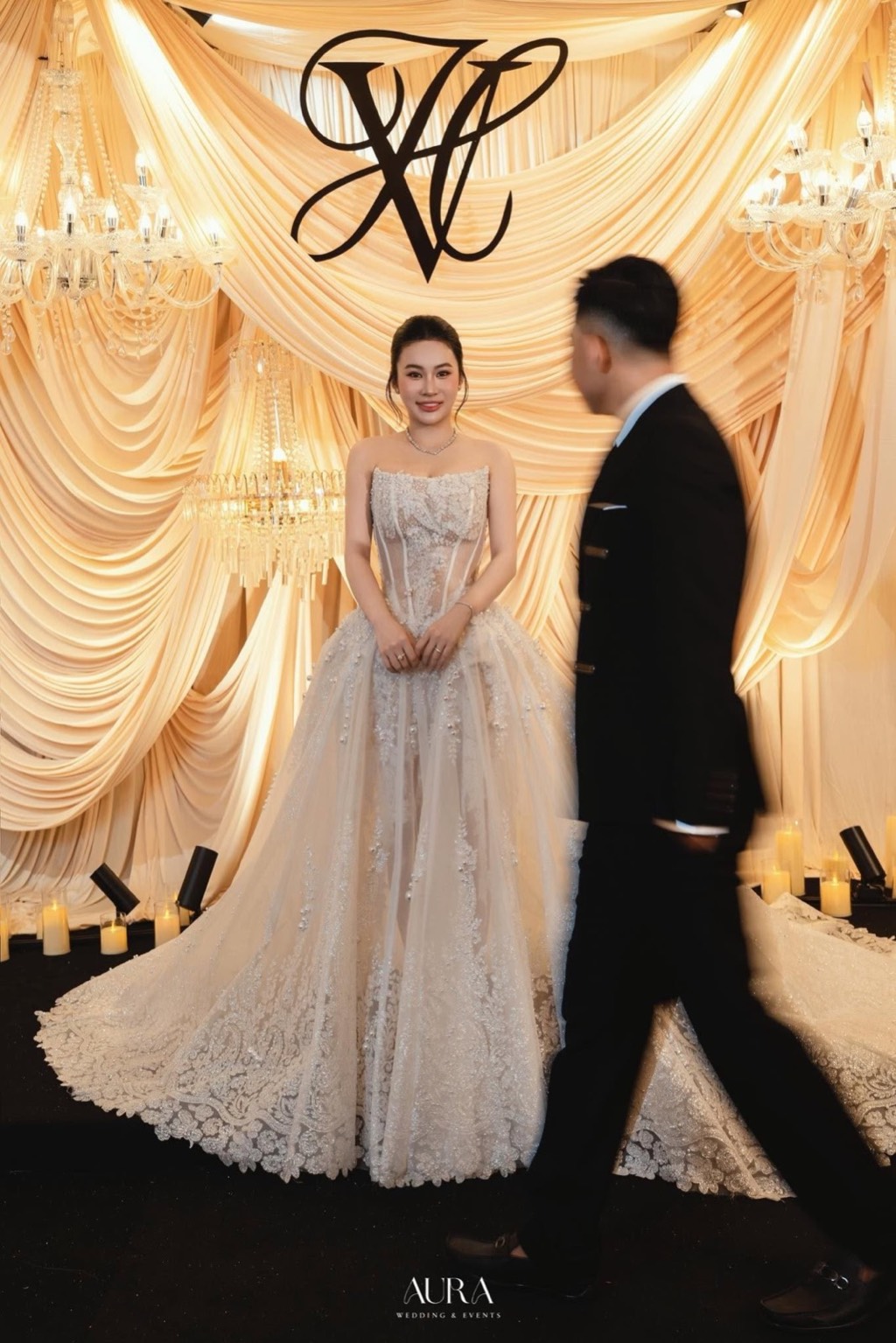 Ivory White — Sân khấu lụa ngà xếp tầng với monogram VH, đèn chùm pha lê và nến, cô dâu đứng giữa
