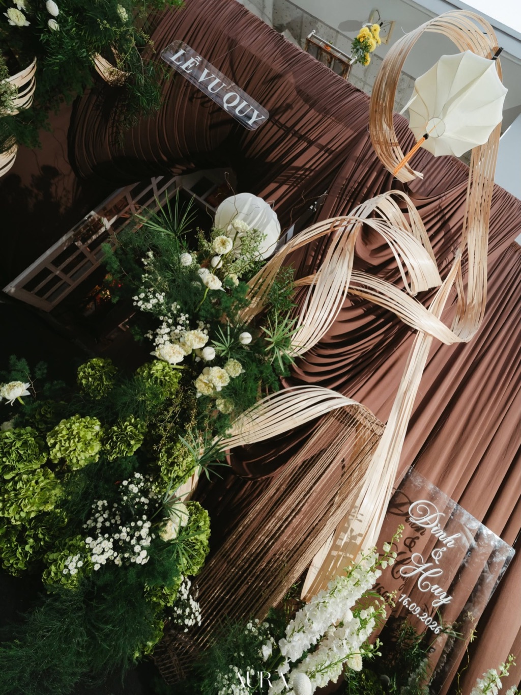 Cổng lễ vu quy nhìn từ trên: dải mây uốn lượn, chiếc dù trắng, khối cẩm tú cầu xanh và hoa trắng trên nền vải nâu