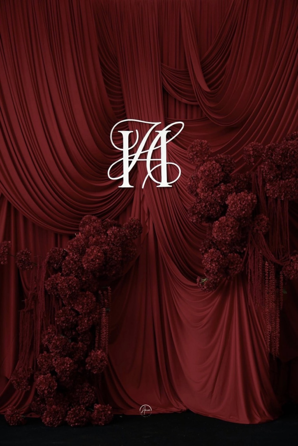 Backdrop nhung đỏ khung dọc với monogram trắng và hai cụm hoa đỏ đối xứng