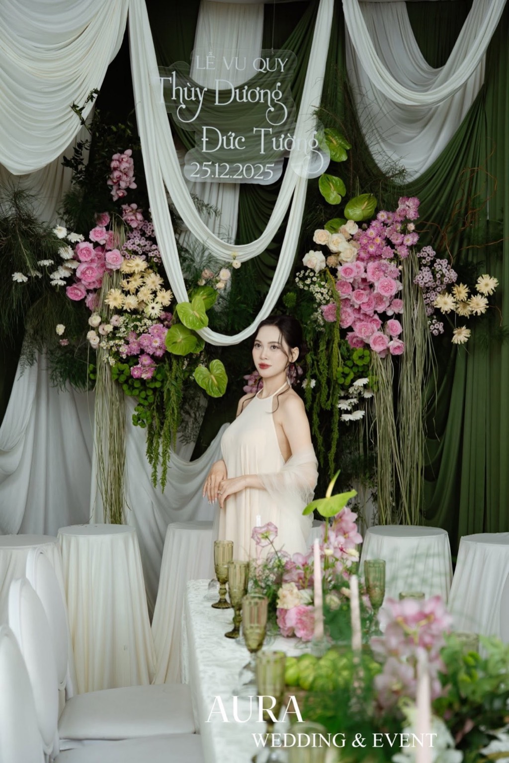 Cô dâu trước lễ đường voan trắng và xanh rêu, bàn tiệc với ly thủy tinh xanh, nến và hoa lan